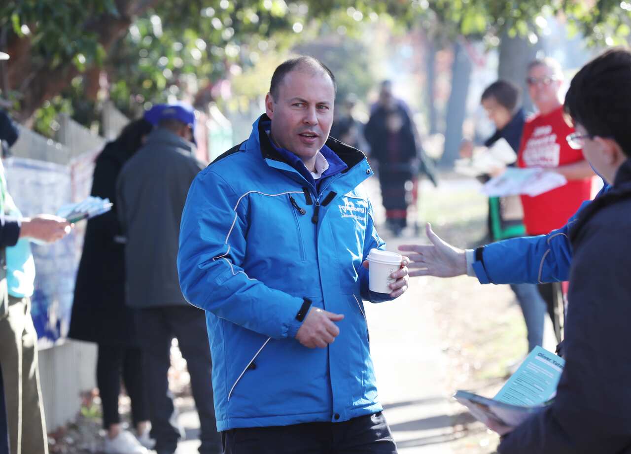 Treasurer Josh Frydenberg wearing a blue coat and carrying a cup of coffee
