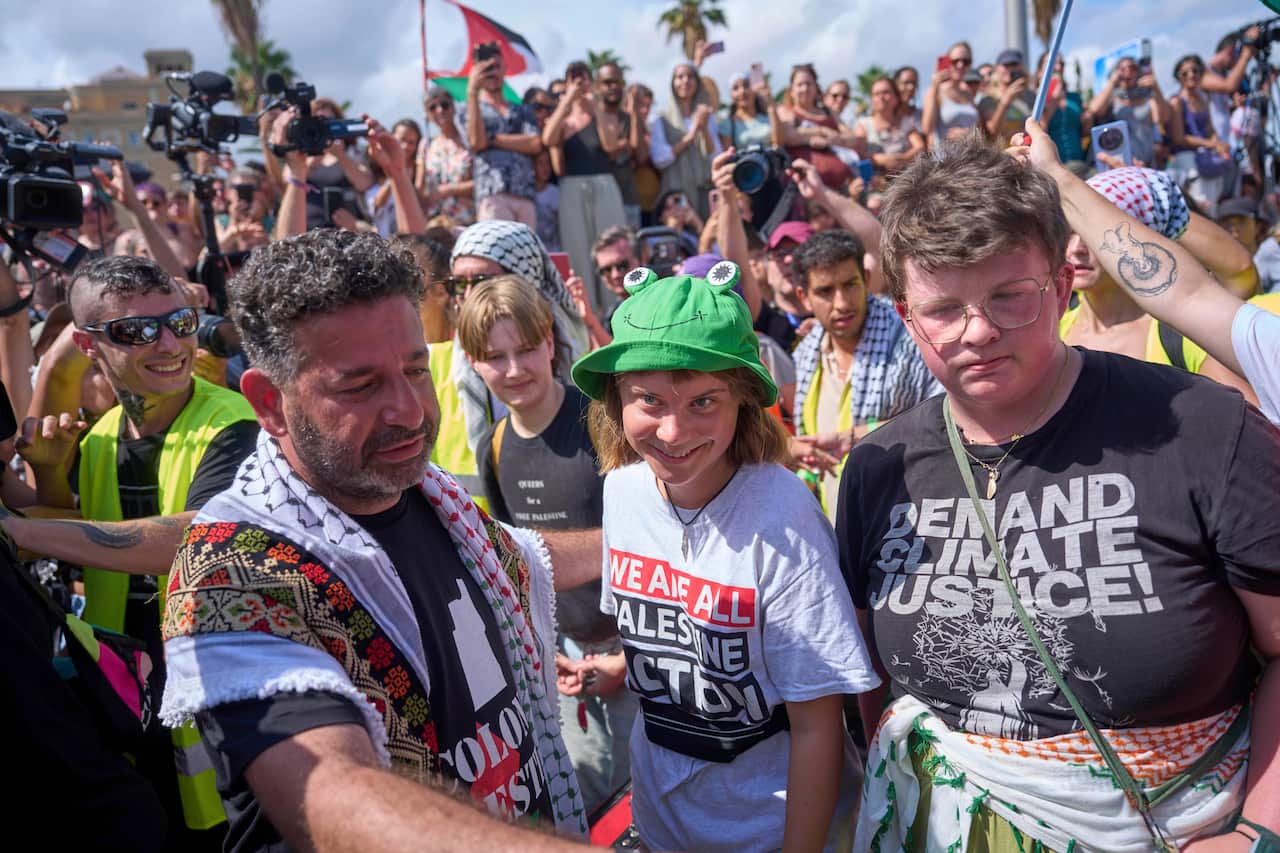 A large group of people outside, some holding banners and flags.