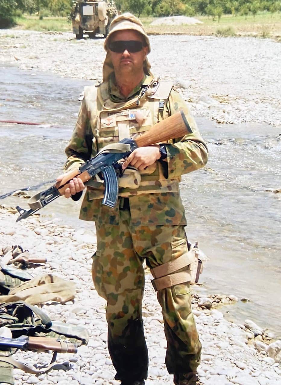 Warren in his defence force uniform, holding a rifle. 