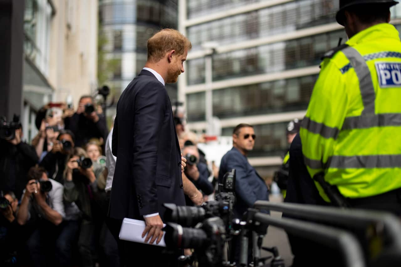 Man in suit leaves court as paparazzi and press cameras photograph his departure