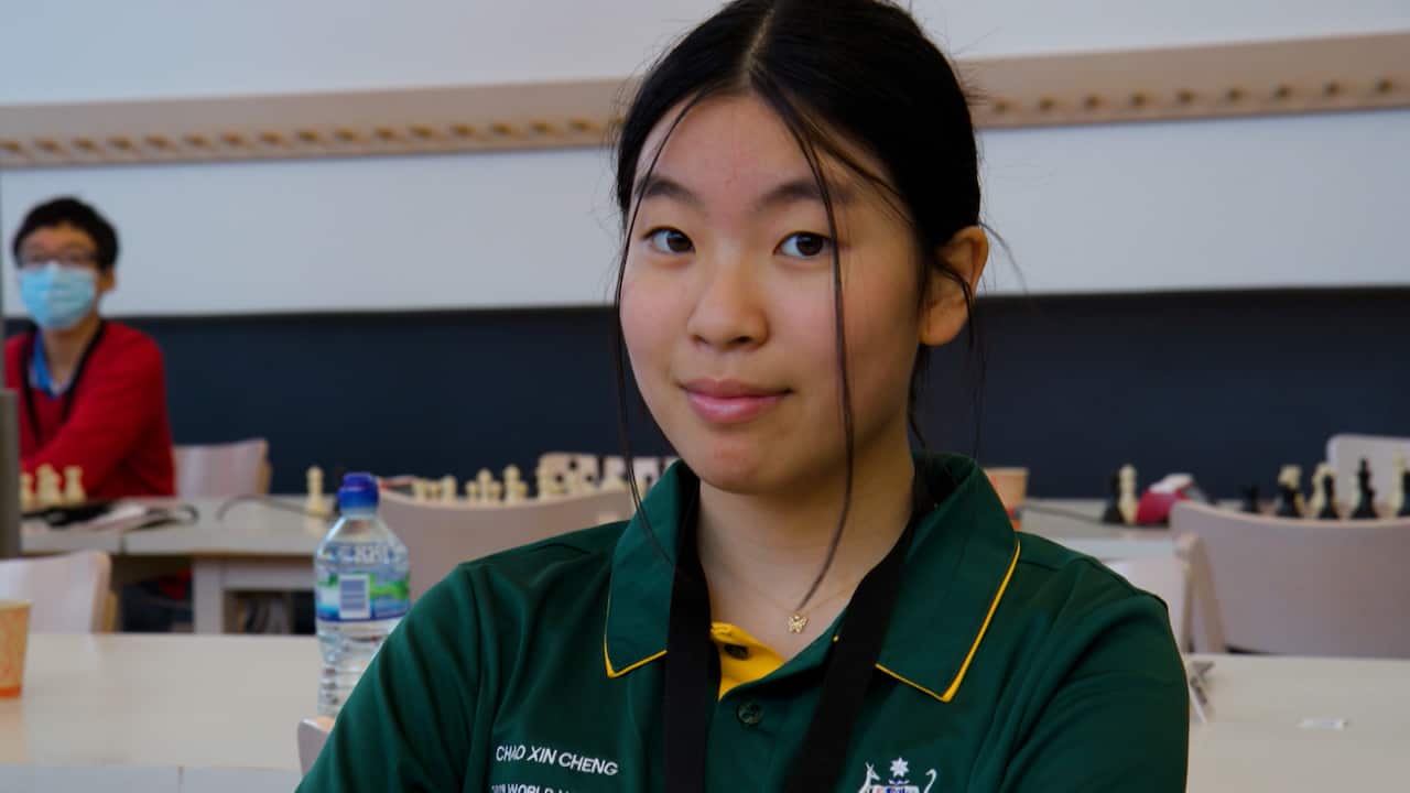 An Asian teenage girl with long dark hair wearing a green and yellow polo shirt 
