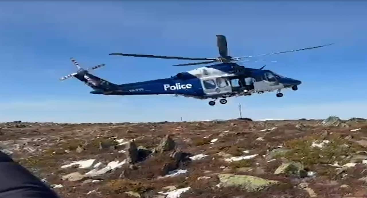 A police helicoper flying above a rocky area 