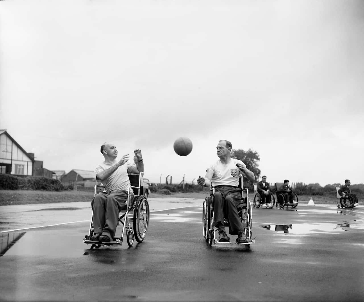 Two men in wheelchairs throw a basketball around.