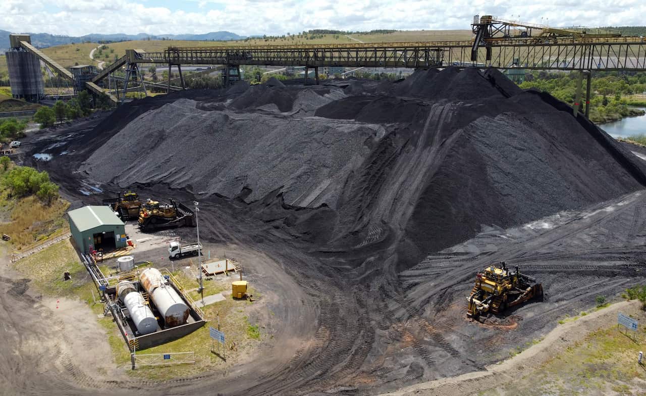 A large pile of coal with associated infrastructure and machinery around it