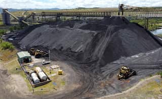 A large pile of coal with associated infrastructure and machinery around it