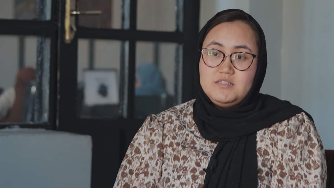 A young woman wearing a black headscarf and prescription glasses 