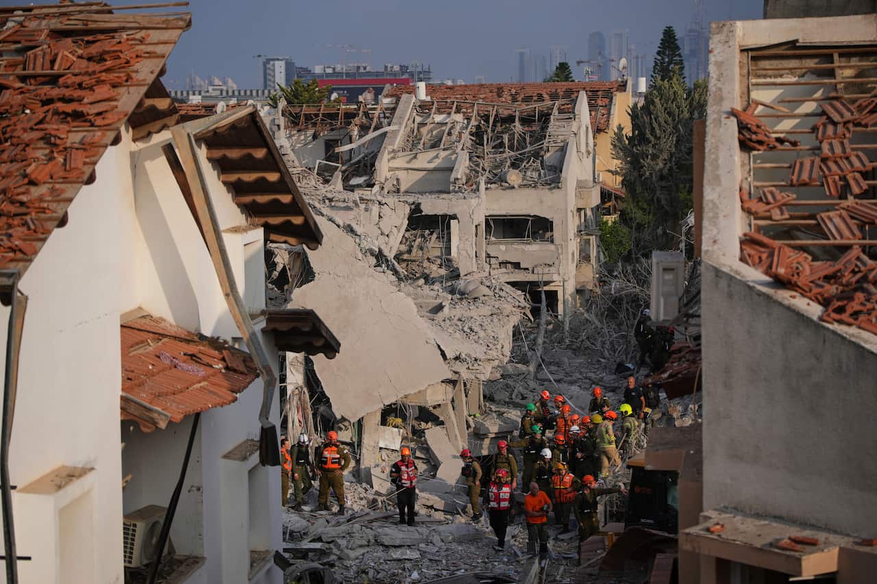 Rescue workers standing amid buildings that have been damaged.