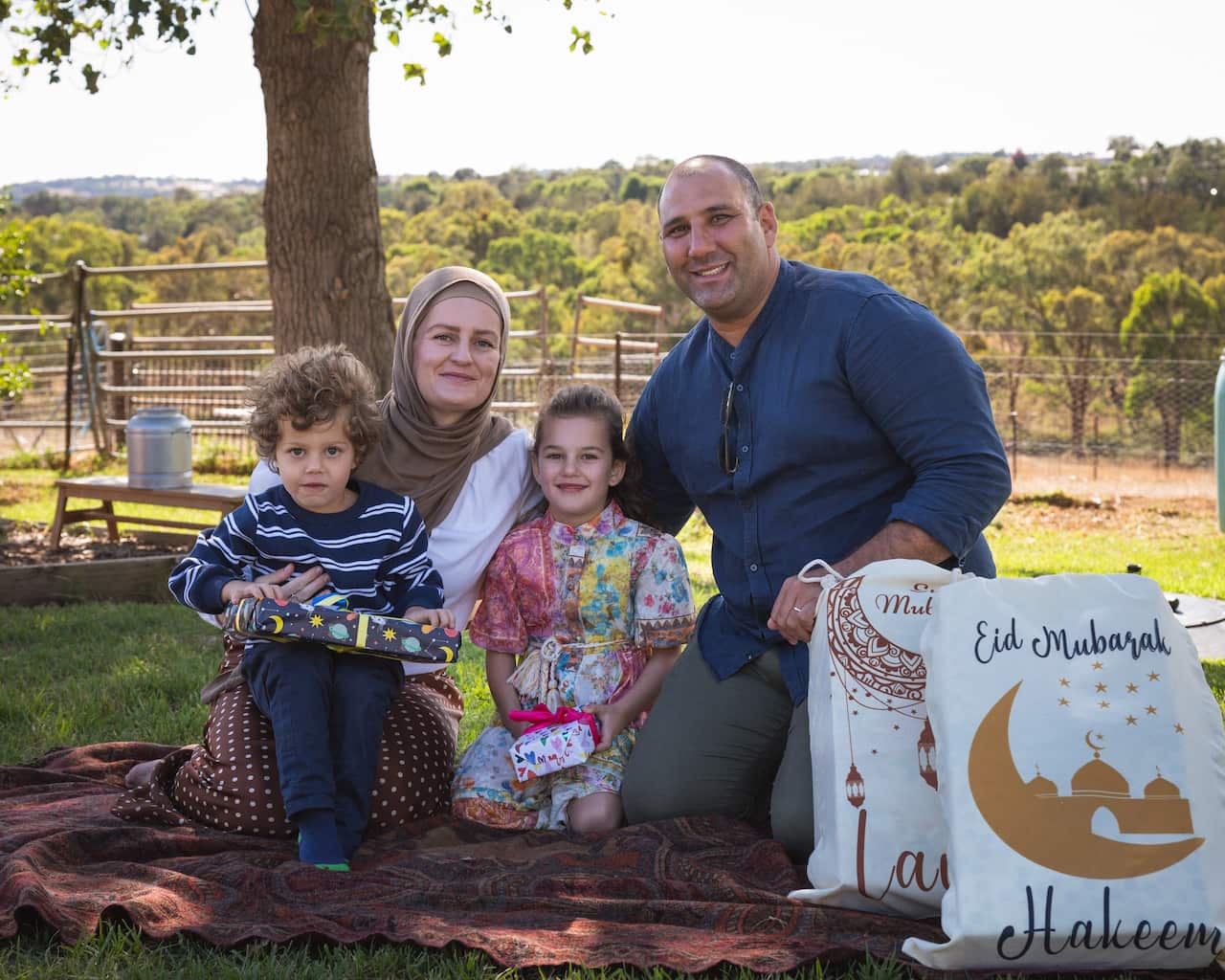 A couple pose outside with their two children.