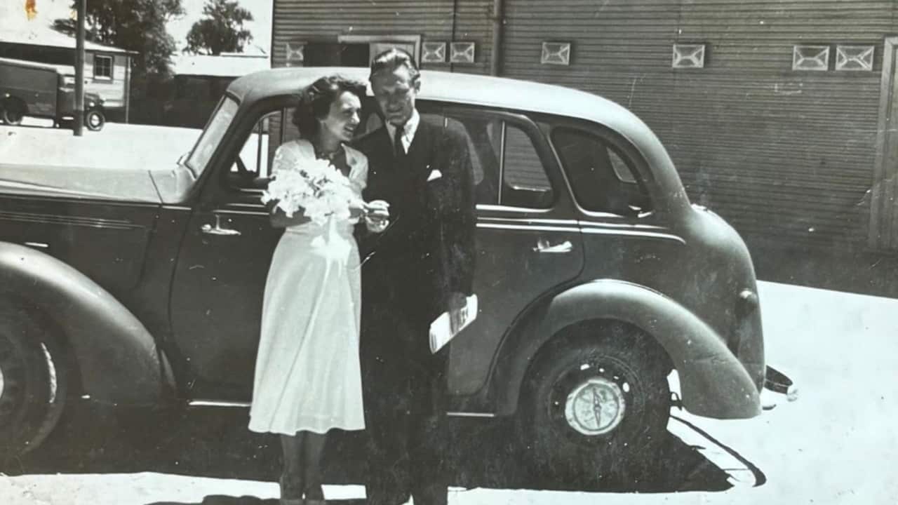 black and white wedding photo from the 50s, a bride and groom in front of a car
