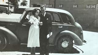 black and white wedding photo from the 50s, a bride and groom in front of a car