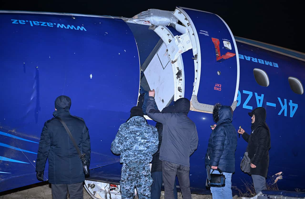 Five people inspect wreckage of a plane.