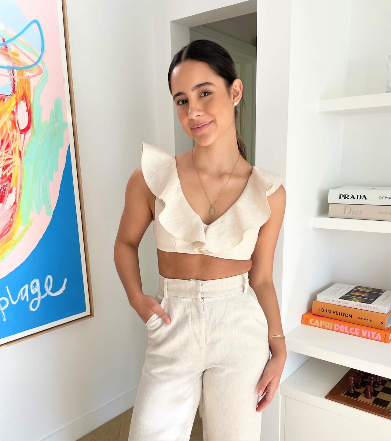 Designer Sofia Abel standing wearing a white ruffle top and pants inside.