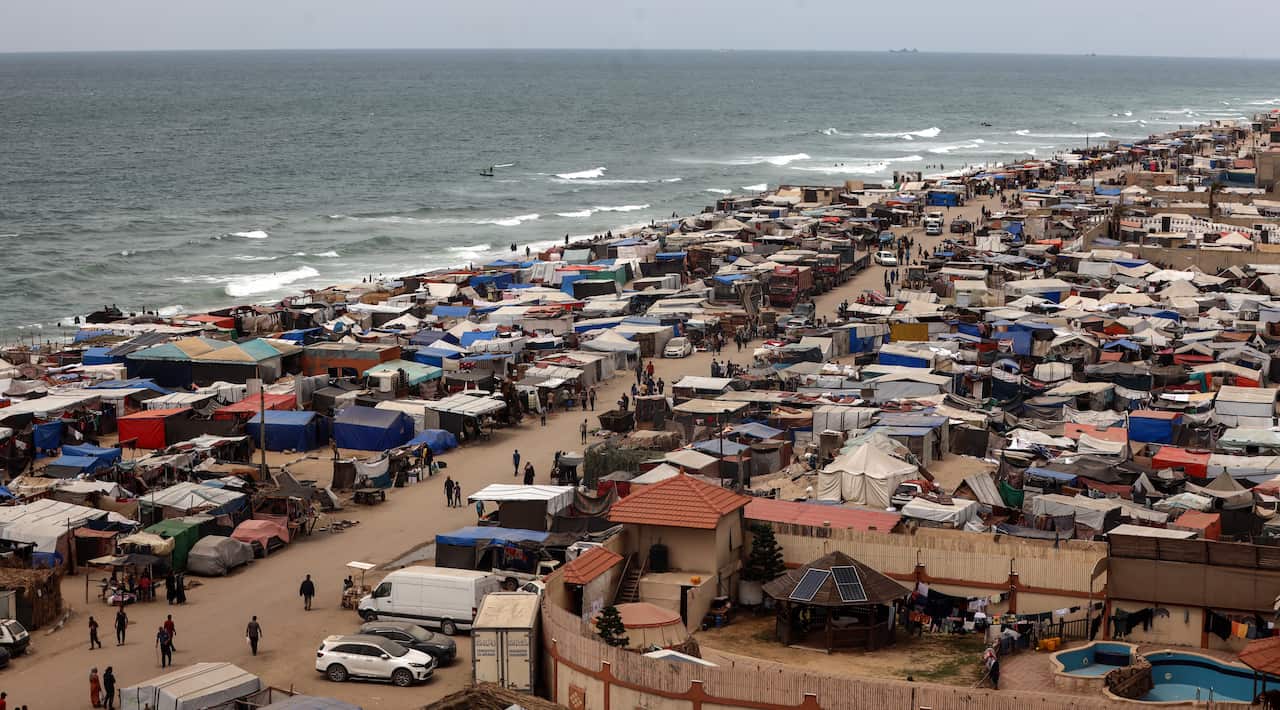 Lots of tents are crowded together near the beach.