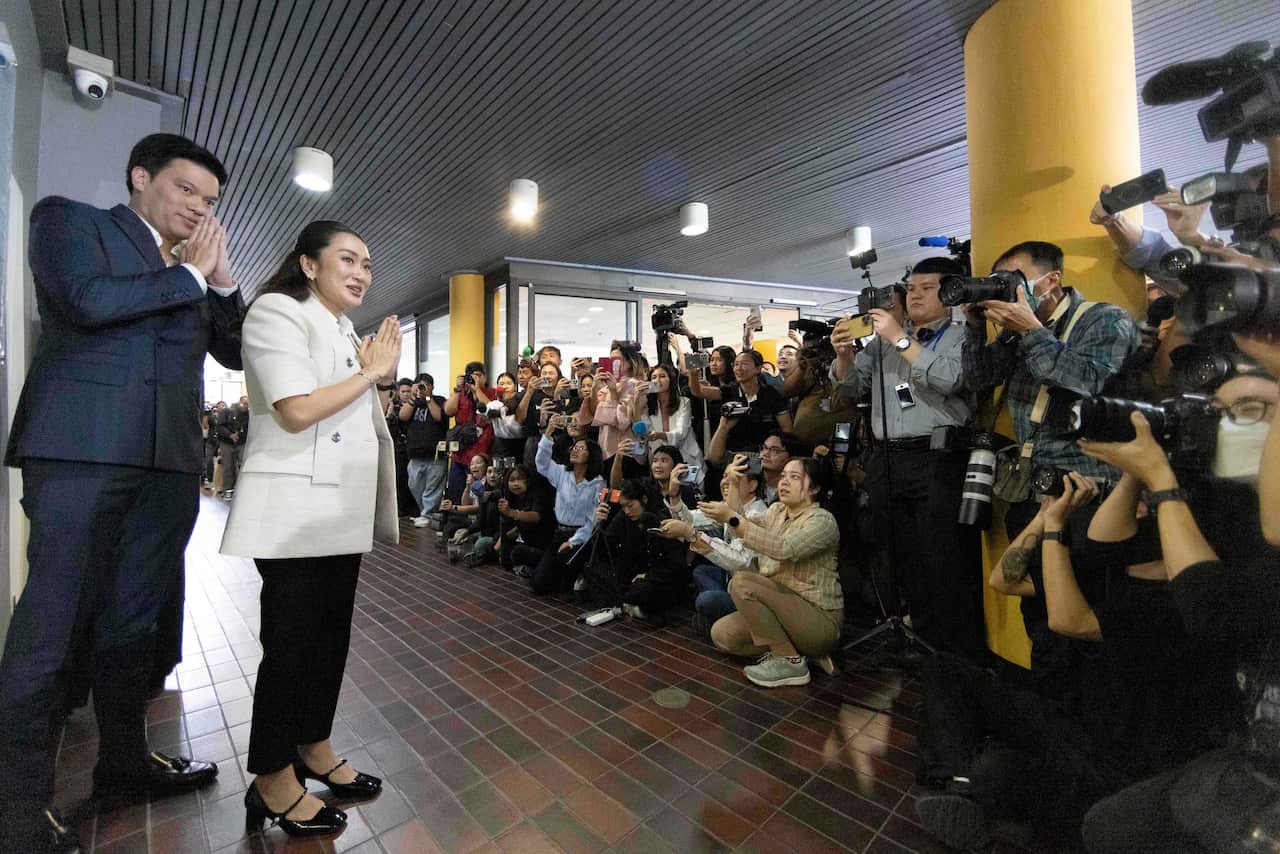A man and a woman greet reporters and photographers