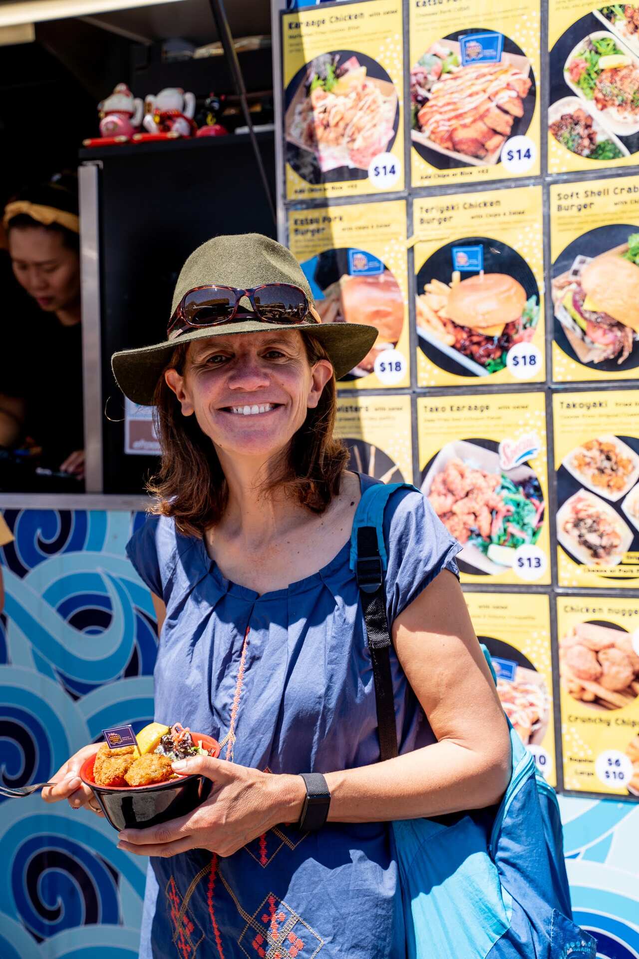 A woman standing in front of a restaurant menu board outside 