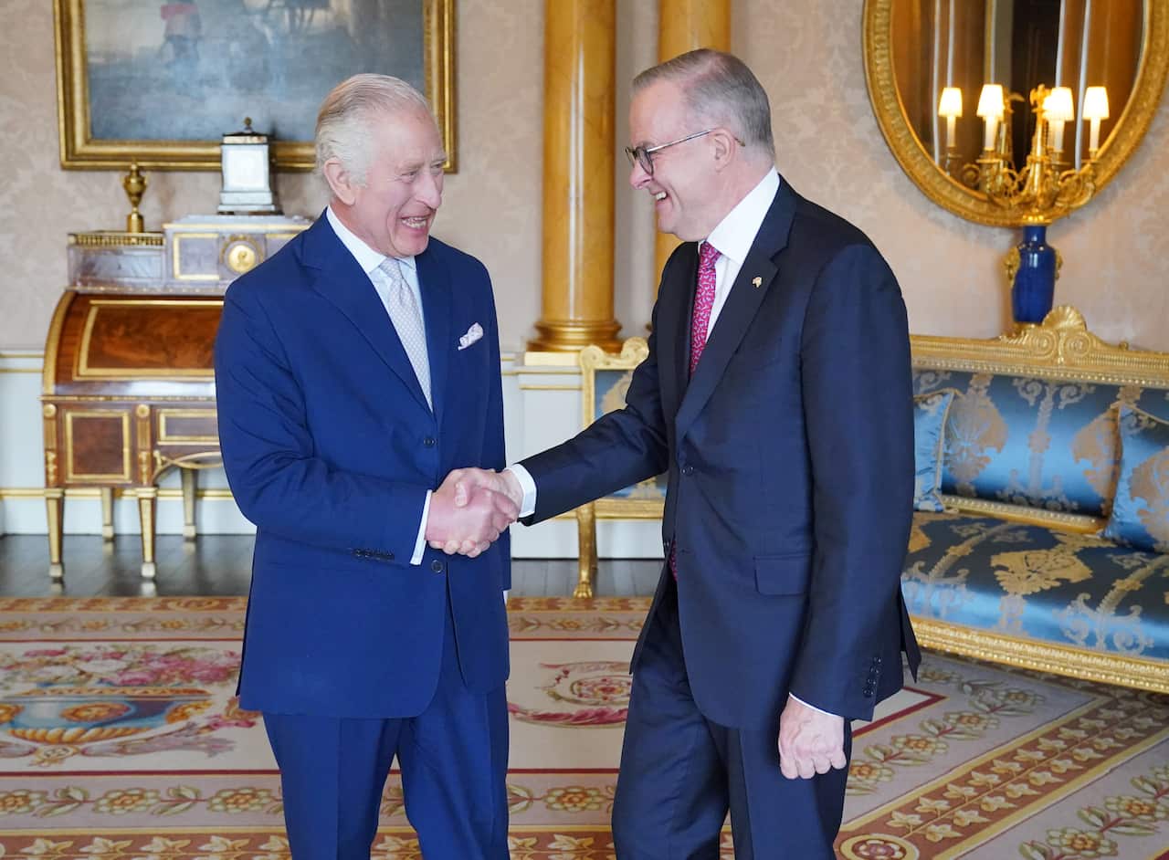 King Charles III (left) shakes hands with Anthony Albanese. Both men are wearing blue suits and standing inside