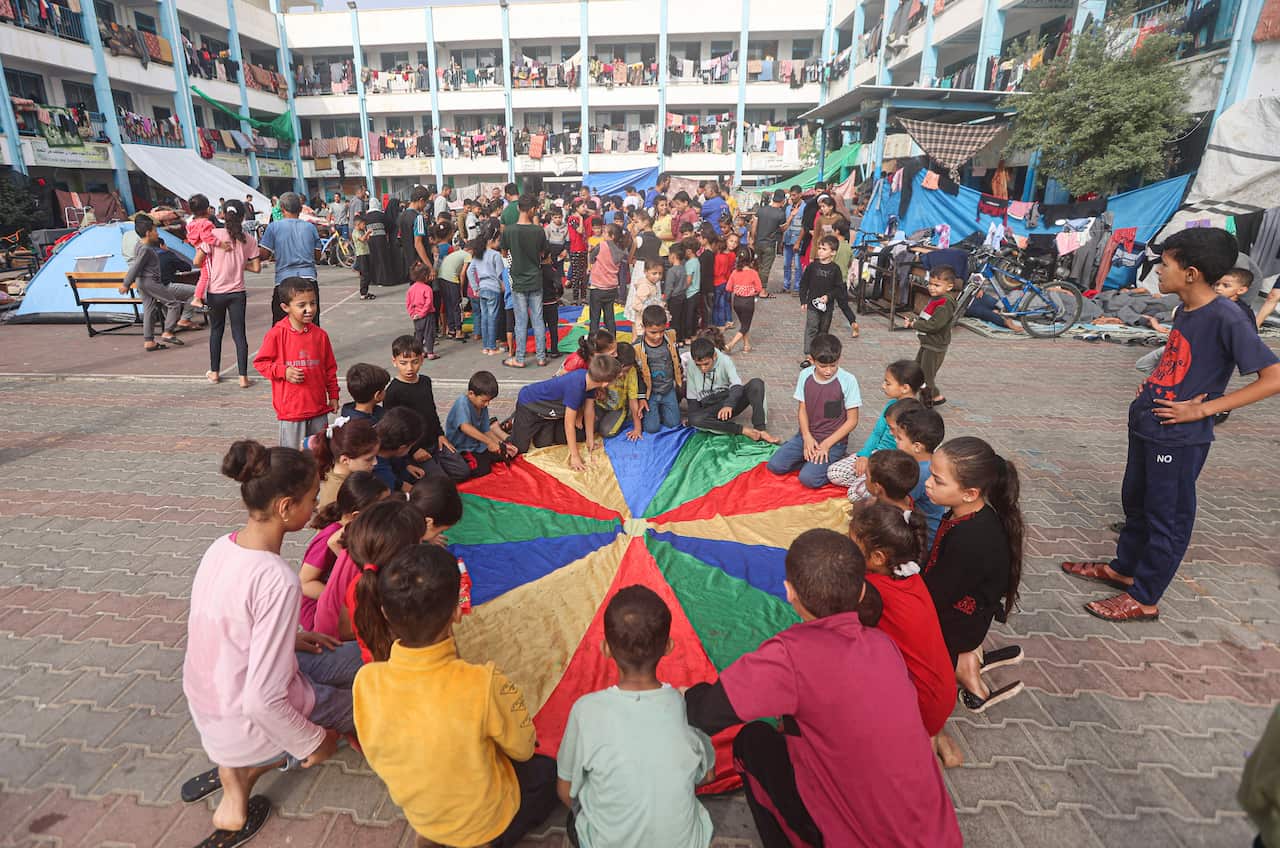 A group of children play a rainbow parachute game 