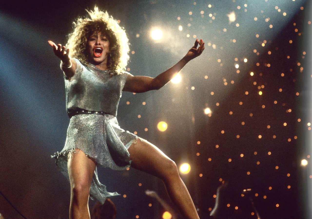 Tina Turner performs on stage in 1990 wearing a silver mini-dress.