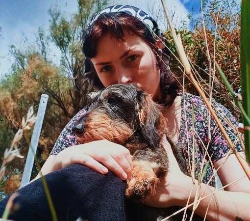 A young woman sitting outside holding a dog 