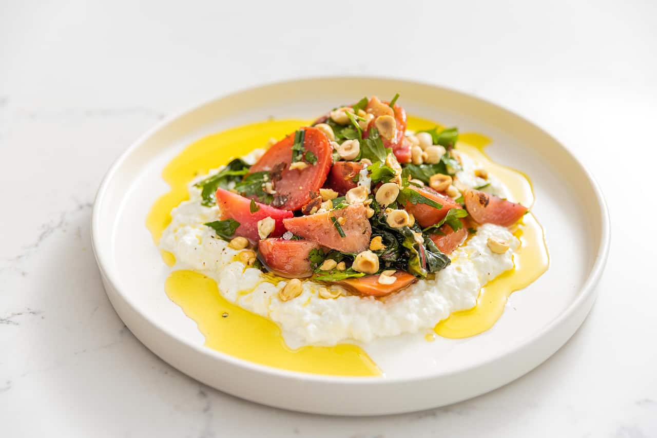 on a modern wide white plate, a salad of pale beets, cut into pieces, sits on bed of goat's curd