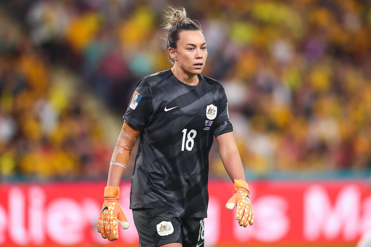 A woman wearing a black uniform walking on a stadium field.