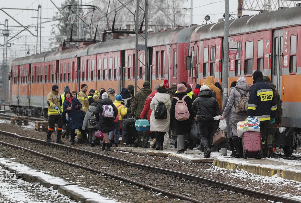 A crowd of people is seen at the side of a train.
