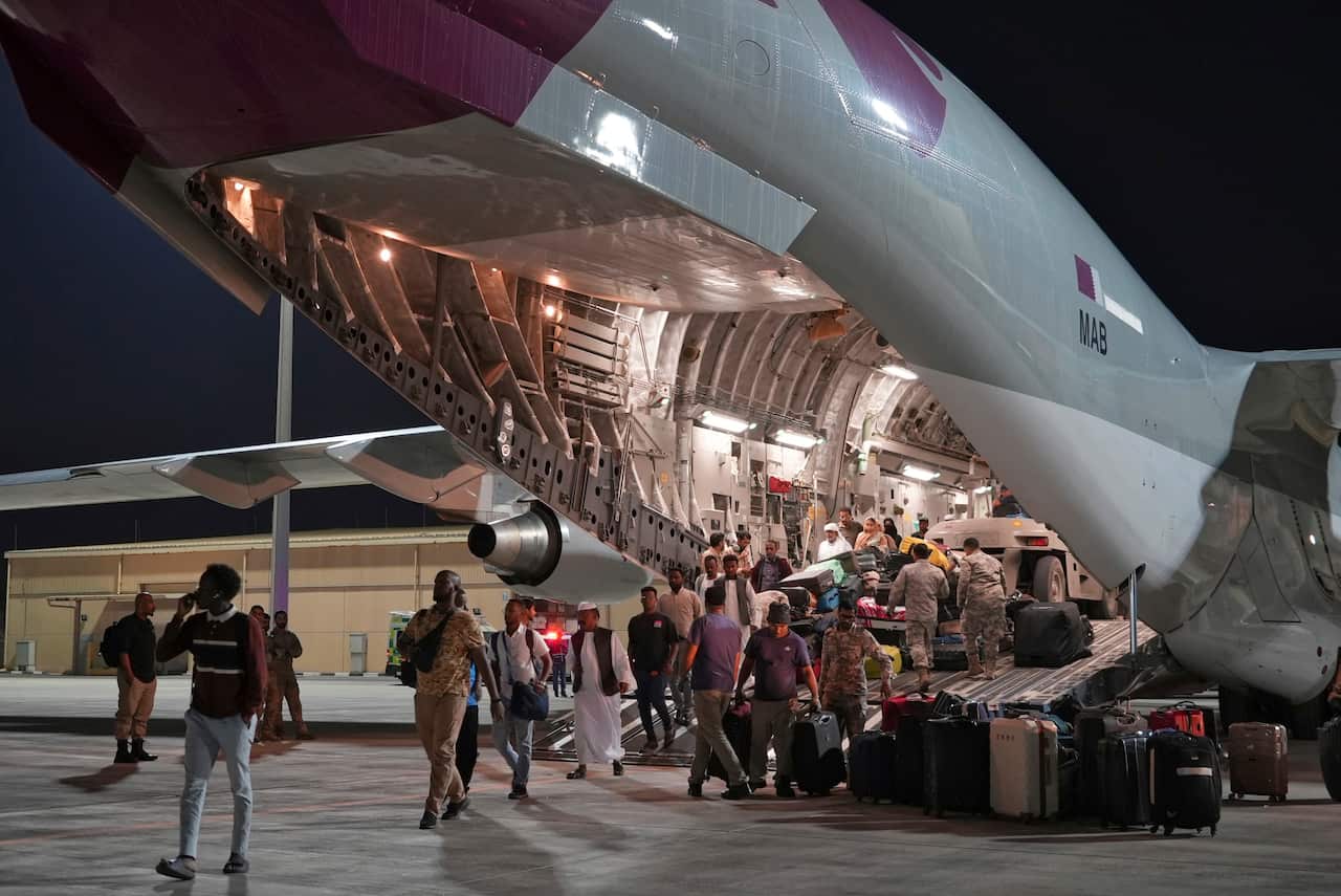 A group of people carry bags onto an aircraft.