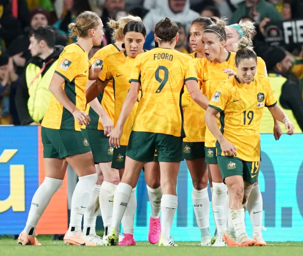 Matildas players in a group celebrating a goal