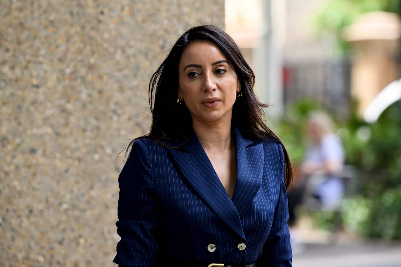 A woman in a blue blazer walking outside.