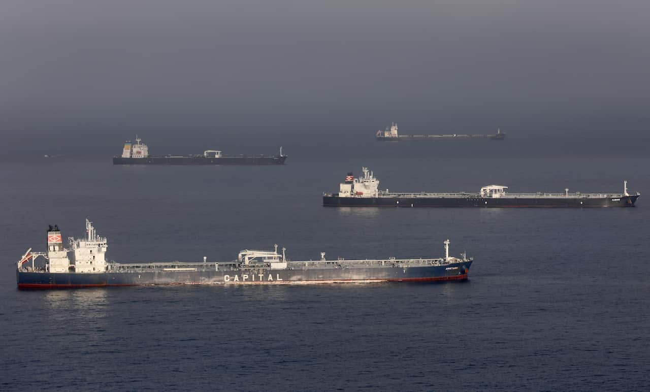 Four large oil tankers are positioned across a calm, hazy sea, with the closest vessel prominently displaying the word "CAPITAL" on its hull.
