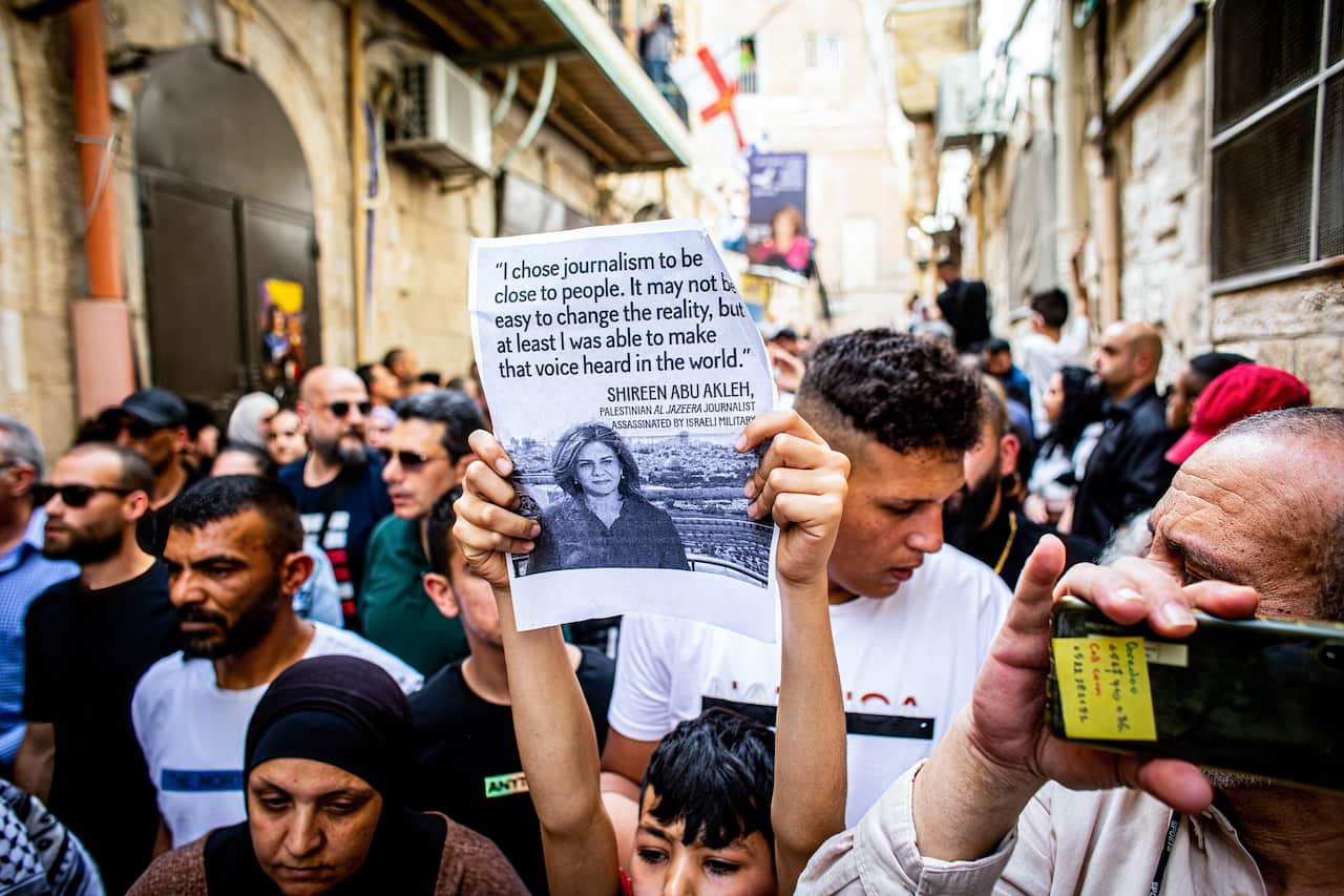 A Palestinian boy chants slogans while holding a placard expressing his opinion during Shireen Abu Aqla's funeral procession. 
