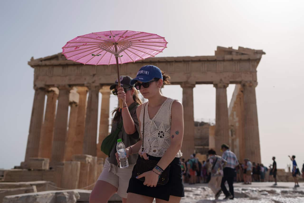 People walking with an umbrella near the Parthenon in central Athens.