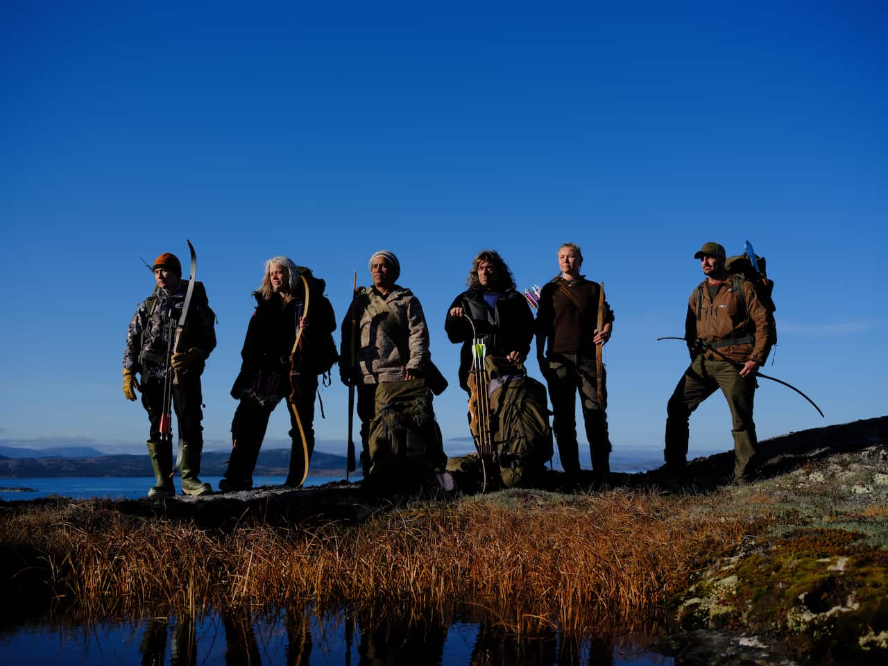 6 contestants from Alone Frozen stand on a hillside