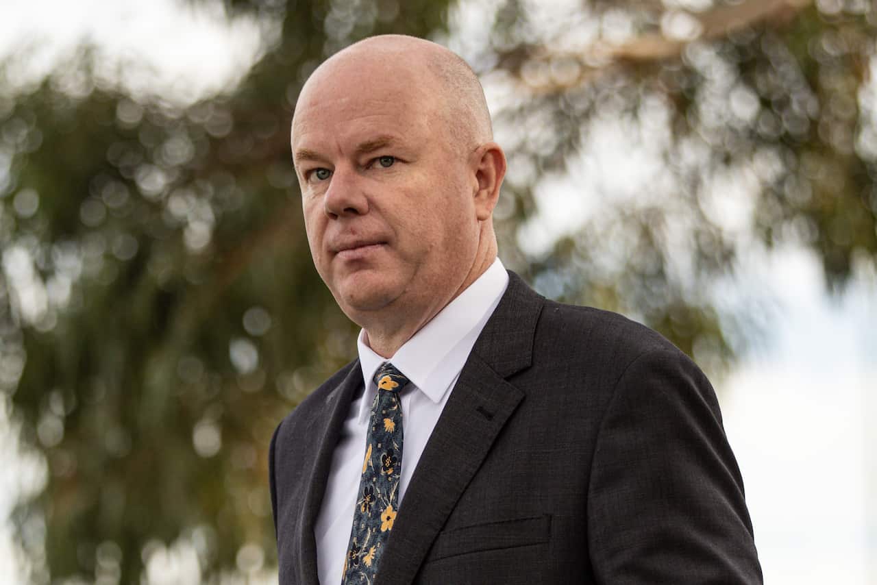 A bald man wearing a suit walking down a street.