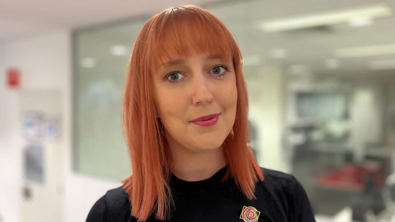 a closeup of a woman with red hair in a black top in an office