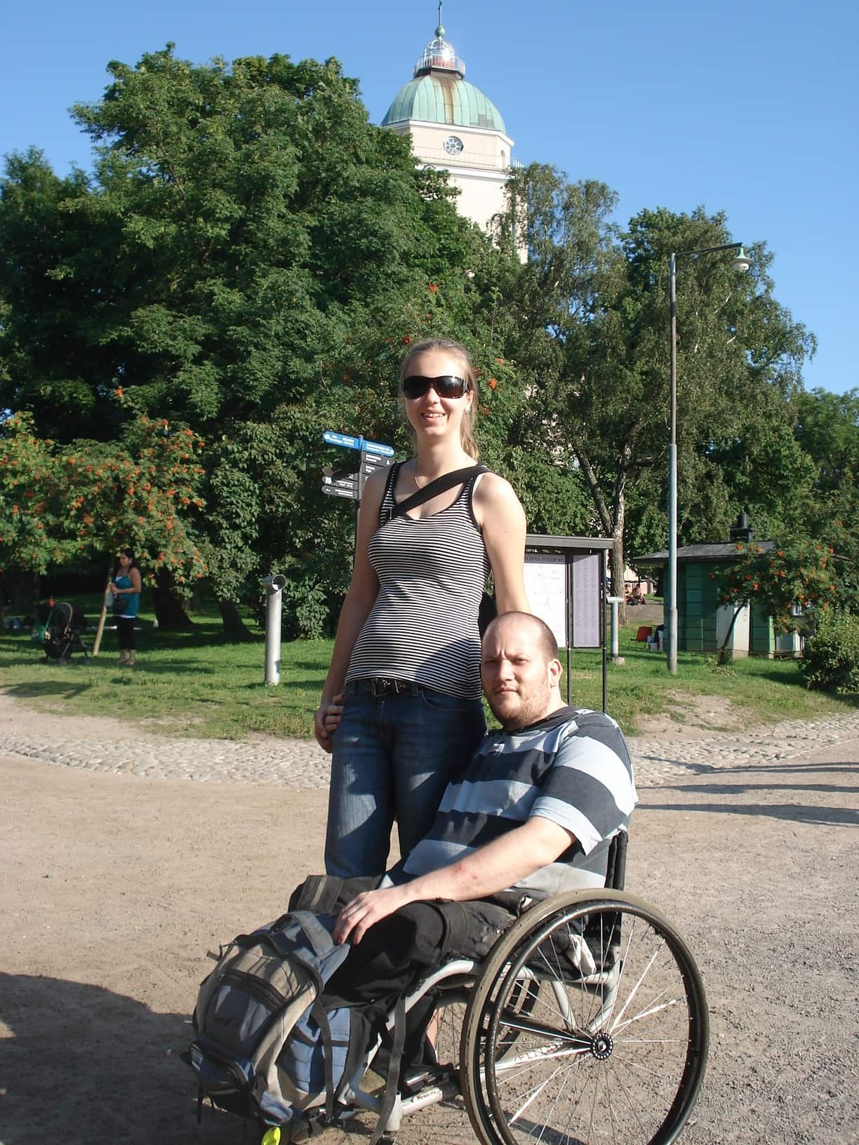 A man who uses a wheelchair is pictured with a woman, who is standing. 