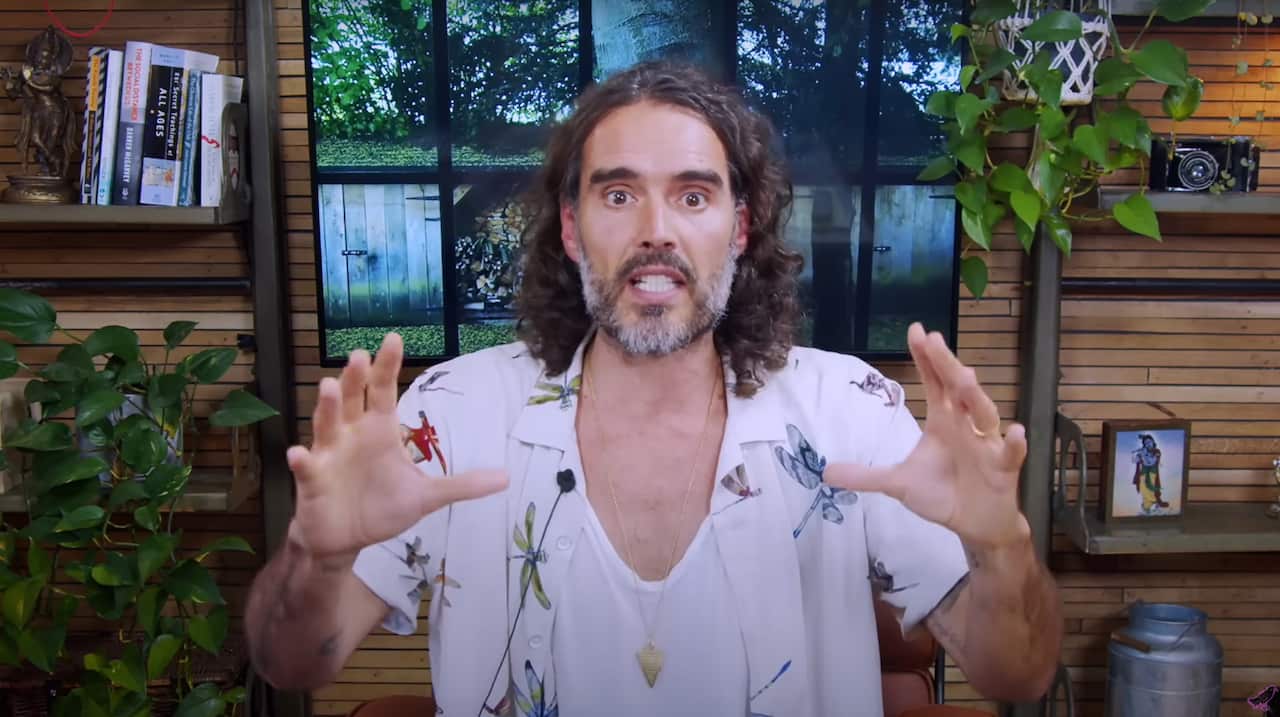 Russell Brand in a white singlet and short with dragonfleis on it 