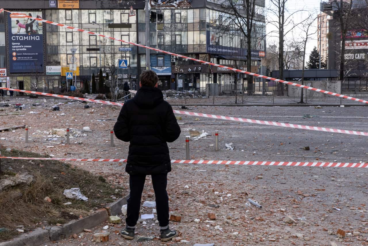 A man looks at damage from a  residential apartment building that was hit by a missile