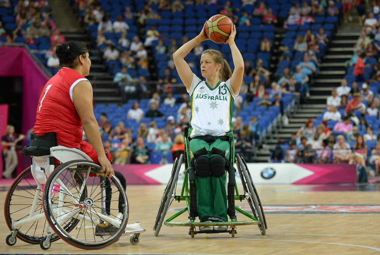 Two women in wheelchairs playing basketball.