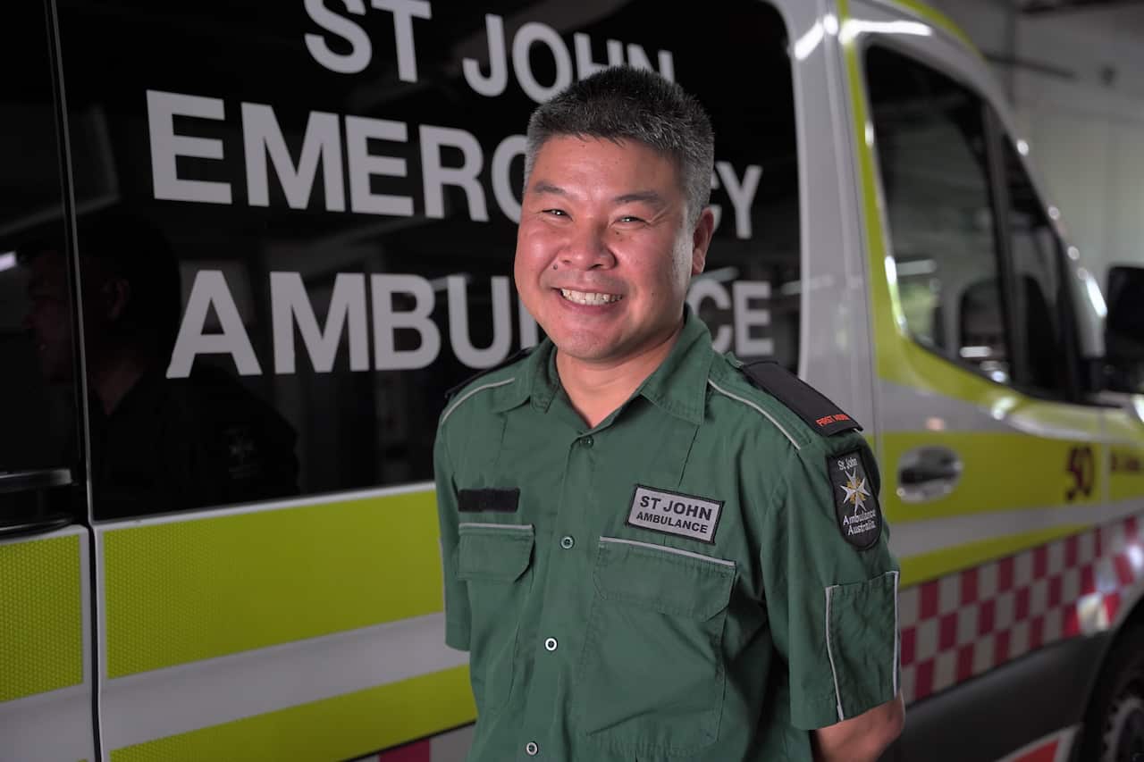A man smiling while standing next to an ambulance.