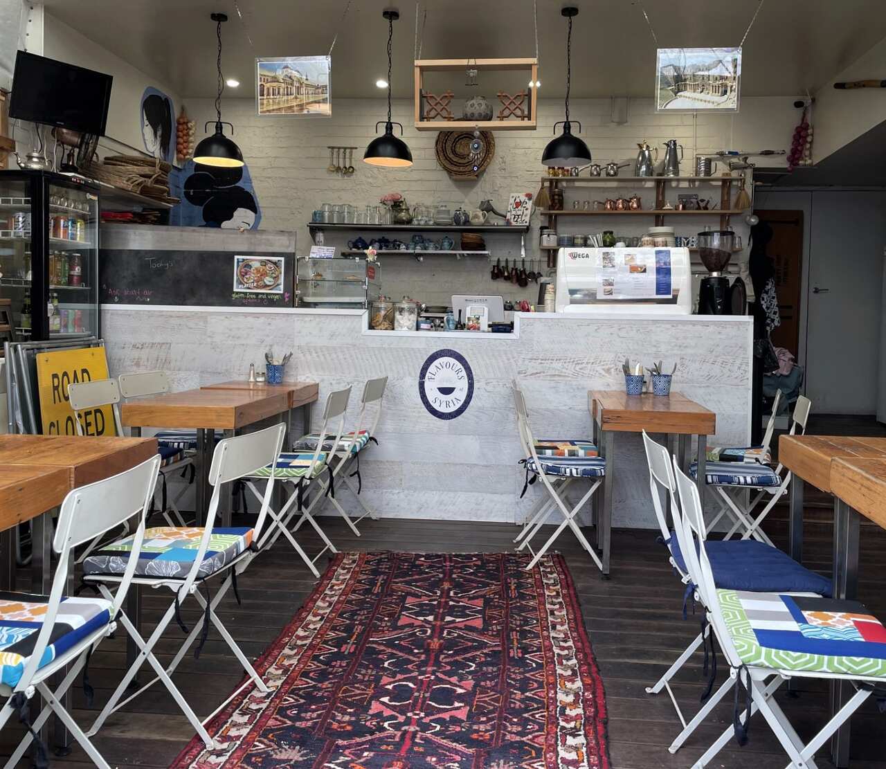 The colourful interior of a small cafe with tables and chairs.