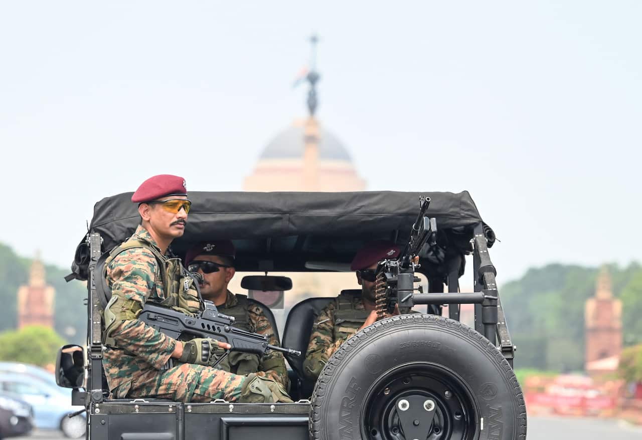Soldiers wearing camo uniform and holding guns in a vehicle.