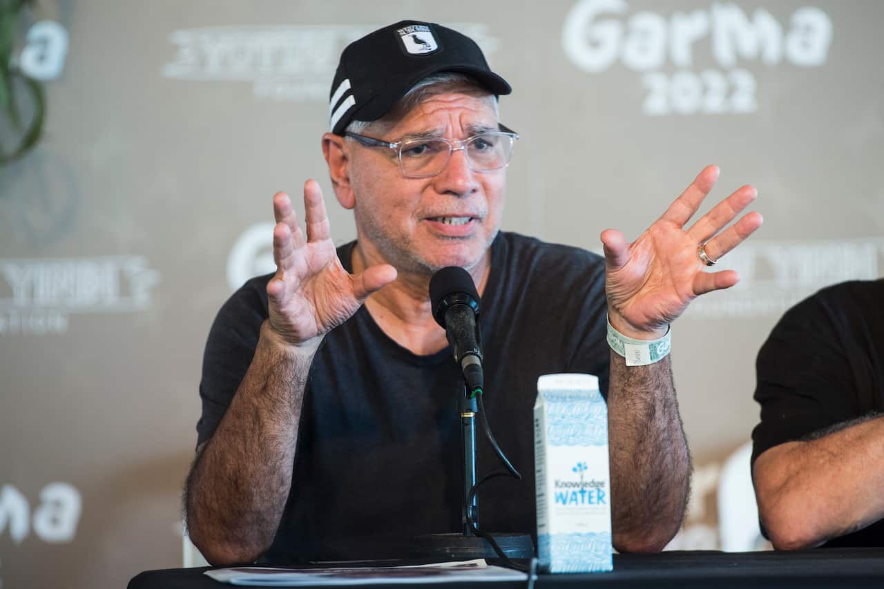 Man in cap and t-shirt speaks into the microphone.