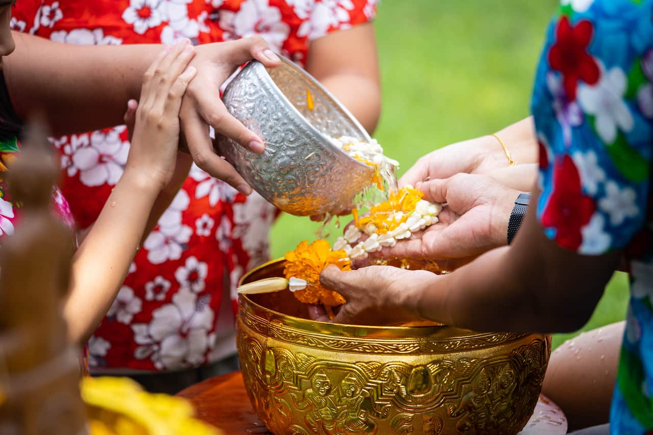 Asian little child girl pouring water on hands of elder senior