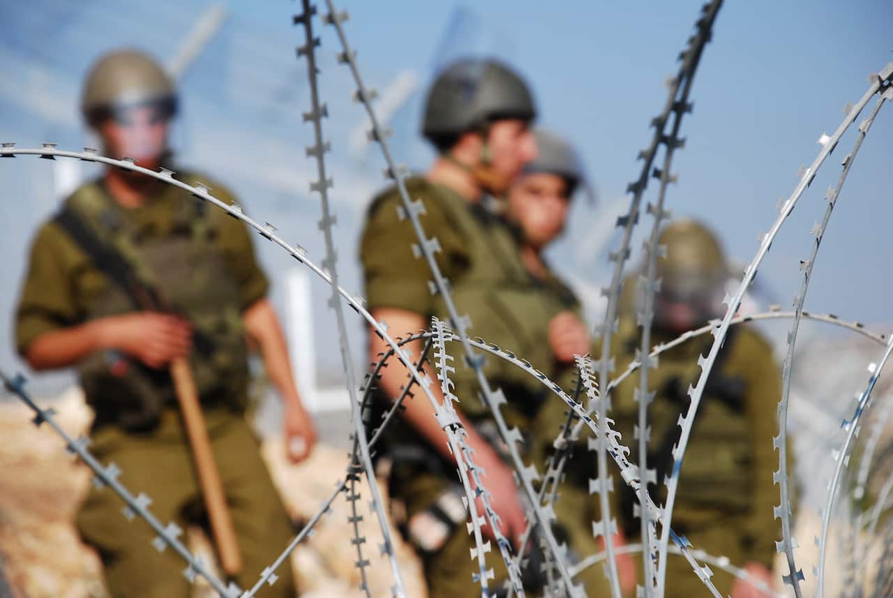 Soldiers behind razor wire.
