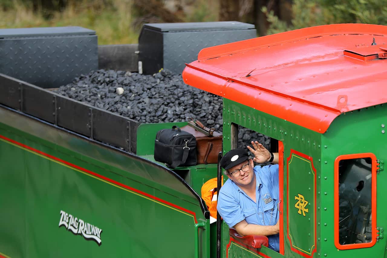 A driver waving from an old-fashioned train.