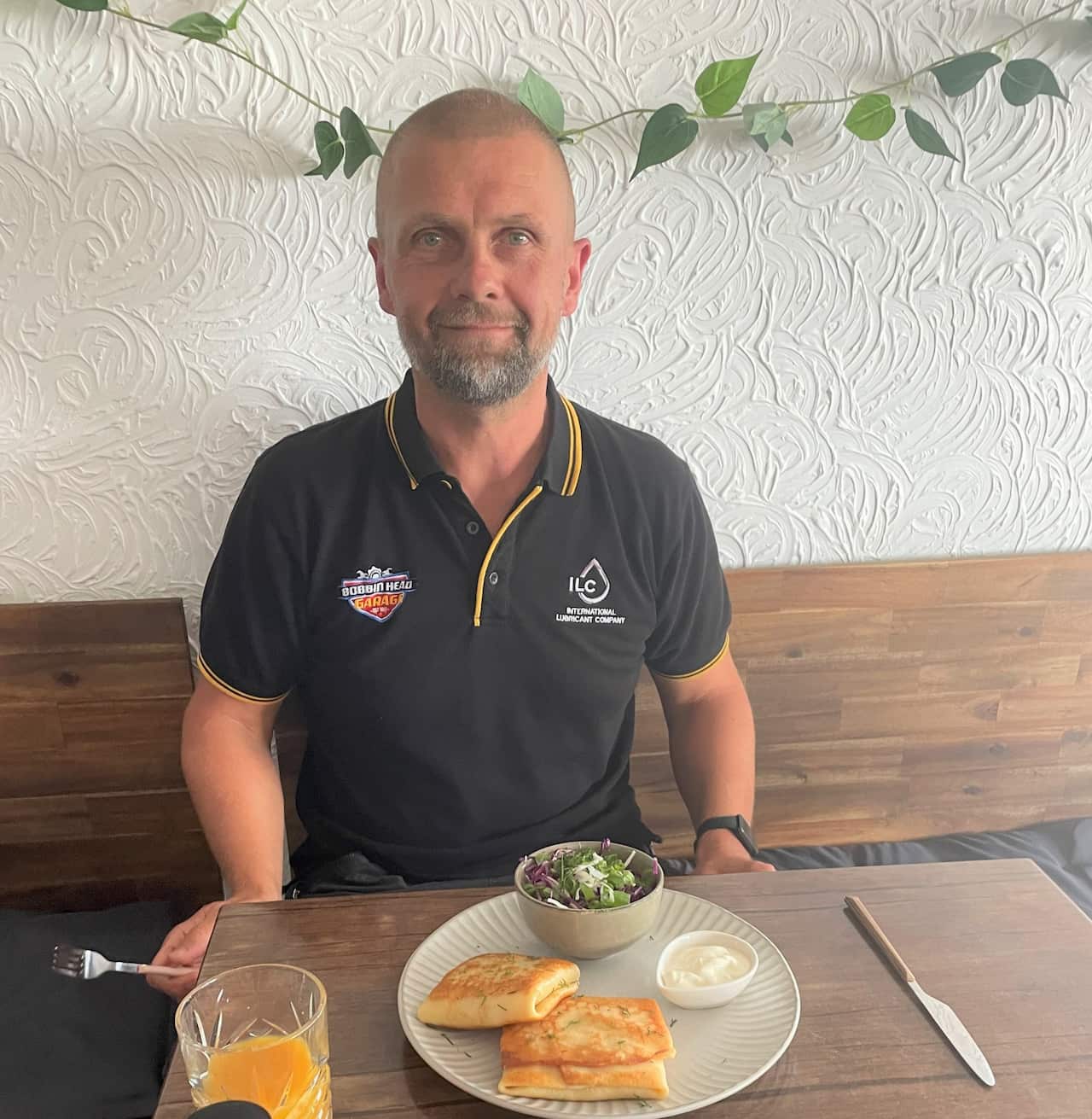 A man sitting at a table with a plate of food and a glass of orange juice in front of him
