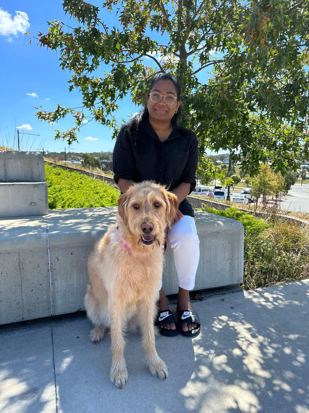 A young woman sitting with a dog in front of her.