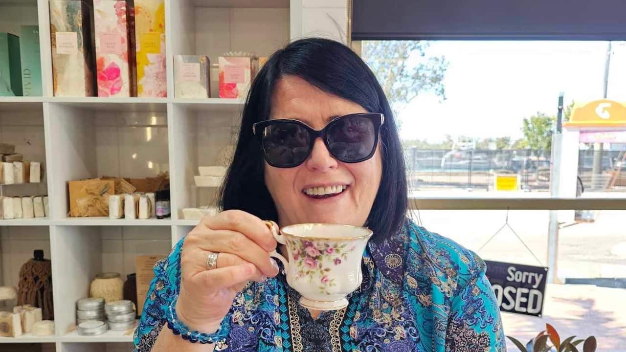 a middle aged woman with a bob having coffee in a cafe