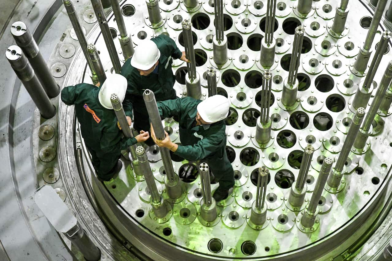 Workers adjusting mock nuclear infrastructure.